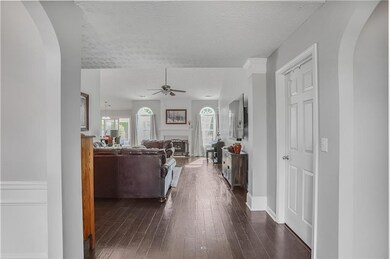 Entry way with tall ceilings looking into family room with cathedral ceiling, ceiling fan, wood floors, arched walkways, new windows and a fireplace