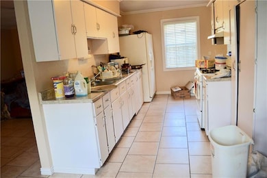 Kitchen with light countertops, ornamental molding, a sink, and white gas range