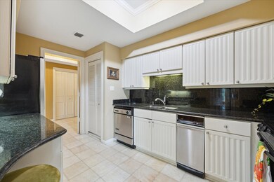 Galley kitchen is crispy white with black granite ocunters.