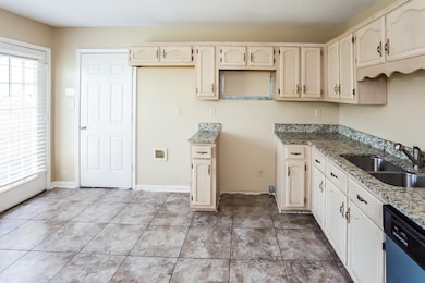 Kitchen with dishwashing machine, stone countertops, and light tile patterned floors