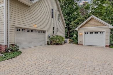 2 car garage featuring decorative paver driveway and detached 1 car garage
