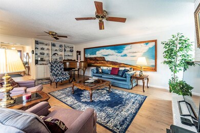 The lovely formal living room features built-in book cases, recent luxury vinyl plank flooring, a fireplace (currently behind TV to right), and a doorway to the back yard