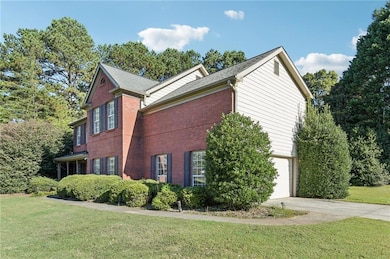 View of home's exterior with brick siding, driveway, a yard, and an attached garage