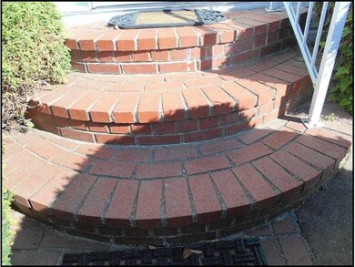 Exterior Front. Curved brick steps lead the way to