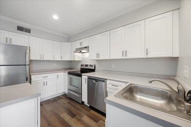 Kitchen featuring white cabinets, crown molding, d
