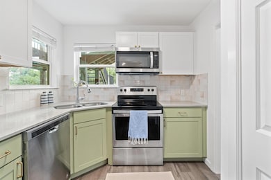 Kitchen with green cabinetry, appliances with sta