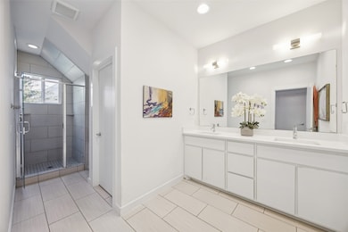 Full bath with double vanity, a shower stall, recessed lighting, and light tile patterned floors