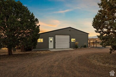 Garage at dusk featuring dirt driveway and a detached garage