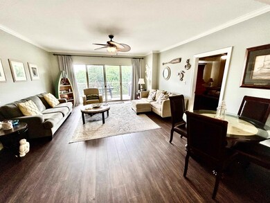 Living room with dark wood-style floors, ornamental molding, and ceiling fan
