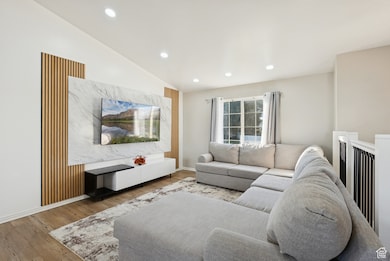 Living area featuring vaulted ceiling, wood finished floors, and recessed lighting