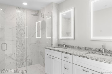 Full bathroom featuring a marble finish shower and double vanity