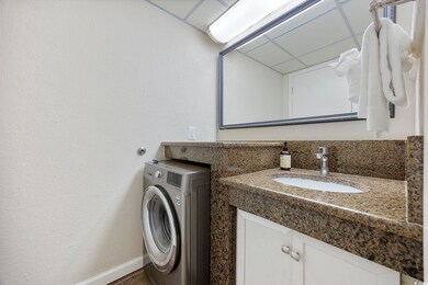 Bathroom featuring washer / dryer, vanity, and bas
