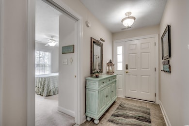 Entryway with baseboards, visible vents, a textured ceiling, and light colored carpet