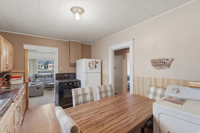 Dining room featuring washer / clothes dryer, ornamental molding, light wood-style flooring, and a wainscoted wall