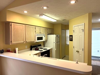 Kitchen with light brown cabinets, a textured ceiling, kitchen peninsula, and white appliances