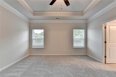 Spare room with light carpet, a tray ceiling, ceiling fan, and ornamental molding