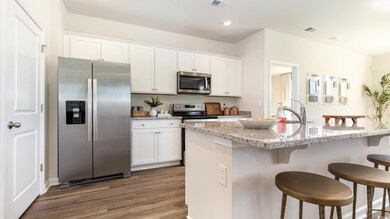 Kitchen featuring appliances with stainless steel finishes, a breakfast bar area, dark wood finished floors, white cabinetry, and a sink