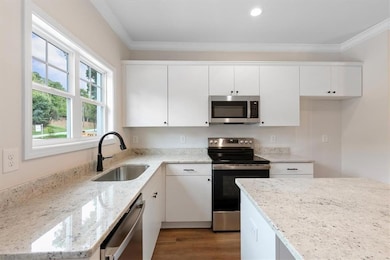Kitchen featuring white cabinets, light stone coun