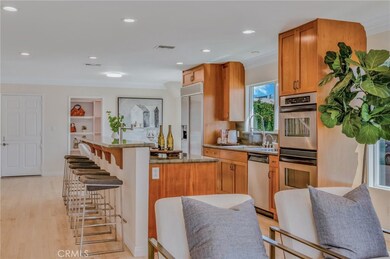 Centrally located kitchen has island with seating, dual ovens and a built-in refrigerator