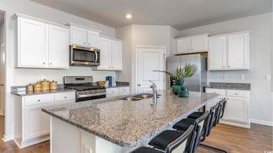 Kitchen with sink, white cabinetry, stainless steel appliances, and a kitchen island with sink