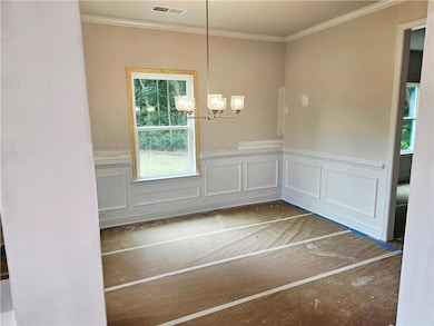 Unfurnished dining area featuring a chandelier, a wainscoted wall, ornamental molding, and a decorative wall