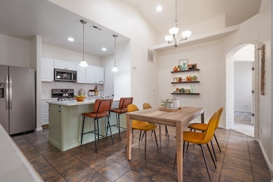 Dining space featuring arched walkways, recessed lighting, a chandelier, dark tile patterned flooring, and lofted ceiling