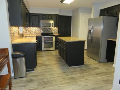 Kitchen with new flooring, granite countertops, stainless appliances. Refrigerator remains