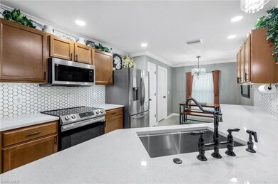 Kitchen with backsplash, appliances with stainless steel finishes, hanging light fixtures, ornamental molding, and brown cabinets