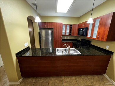 Kitchen with black appliances, a sink, a peninsula, and glass insert cabinets
