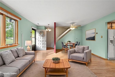Living area with light wood-style floors, a ceiling fan, and a chandelier