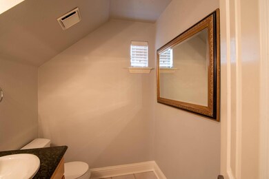 1/2 Bathroom with vanity, lofted ceiling, and toil