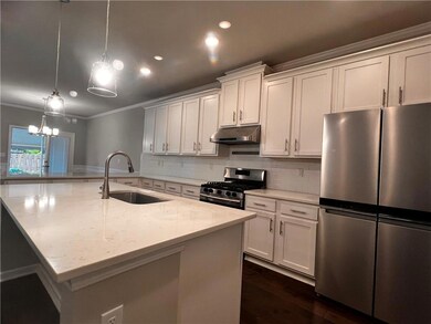 Kitchen featuring stainless steel appliances, under cabinet range hood, a sink, crown molding, and decorative backsplash