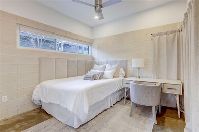 Bedroom with concrete floors, tile walls, and cei