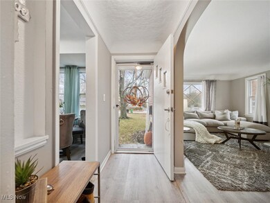 Entrance foyer with light wood-style flooring, arched walkways, and a textured ceiling