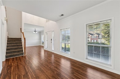 Unfurnished living room with crown molding, a chandelier, stairway, plenty of natural light, and dark wood finished floors
