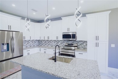 Kitchen with a kitchen island with sink, stainless steel appliances, white cabinets, tasteful backsplash, and recessed lighting