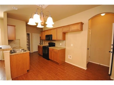 Kitchen with black appliances, arched walkways, a