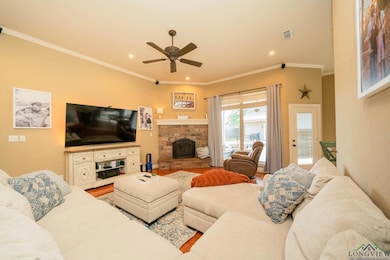 Living room featuring ceiling fan, recessed lighting, ornamental molding, wood finished floors, and a fireplace with raised hearth