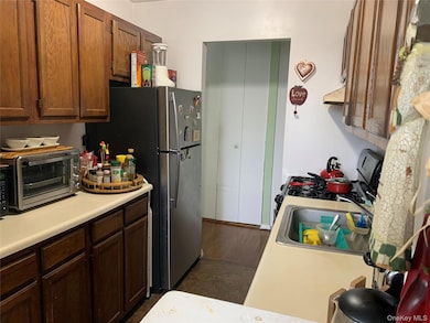 Kitchen featuring light countertops, appliances with stainless steel finishes, under cabinet range hood, and brown cabinets