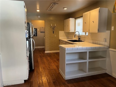 Kitchen featuring tile counters, a sink, open shel