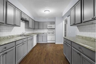 Kitchen featuring stove, backsplash, dark hardwood