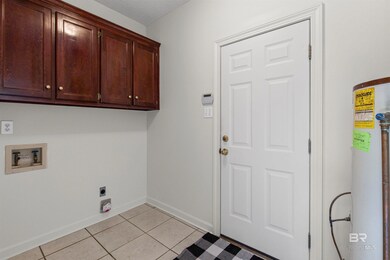 Laundry room featuring light tile patterned floors, hookup for a washing machine, cabinet space, electric dryer hookup, and water heater