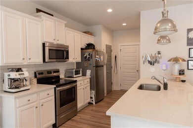 Kitchen with stainless steel appliances, a sink, backsplash, light wood-style floors, and recessed lighting