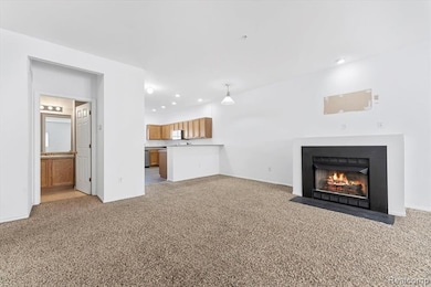 Unfurnished living room with light carpet, a fireplace with flush hearth, and recessed lighting