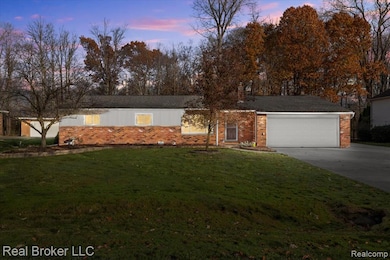 Ranch-style home with a lawn, concrete driveway, brick siding, and an attached garage