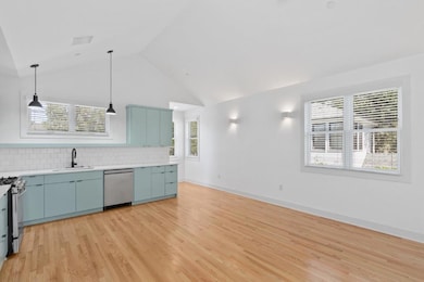 Kitchen featuring blue cabinets, appliances with stainless steel finishes, light wood-style flooring, high vaulted ceiling, and backsplash