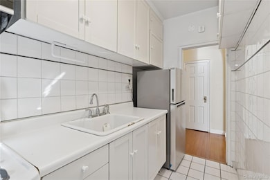 Kitchen featuring white cabinets, light countertops, freestanding refrigerator, and light tile patterned floors
