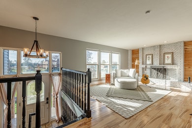 Living area featuring a chandelier, a textured ceiling, wood finished floors, and a brick fireplace