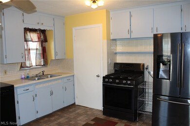 Kitchen featuring black appliances, wood cabinets, sin and vinyl floors