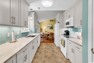 Kitchen with white appliances, a sink, backsplash,
